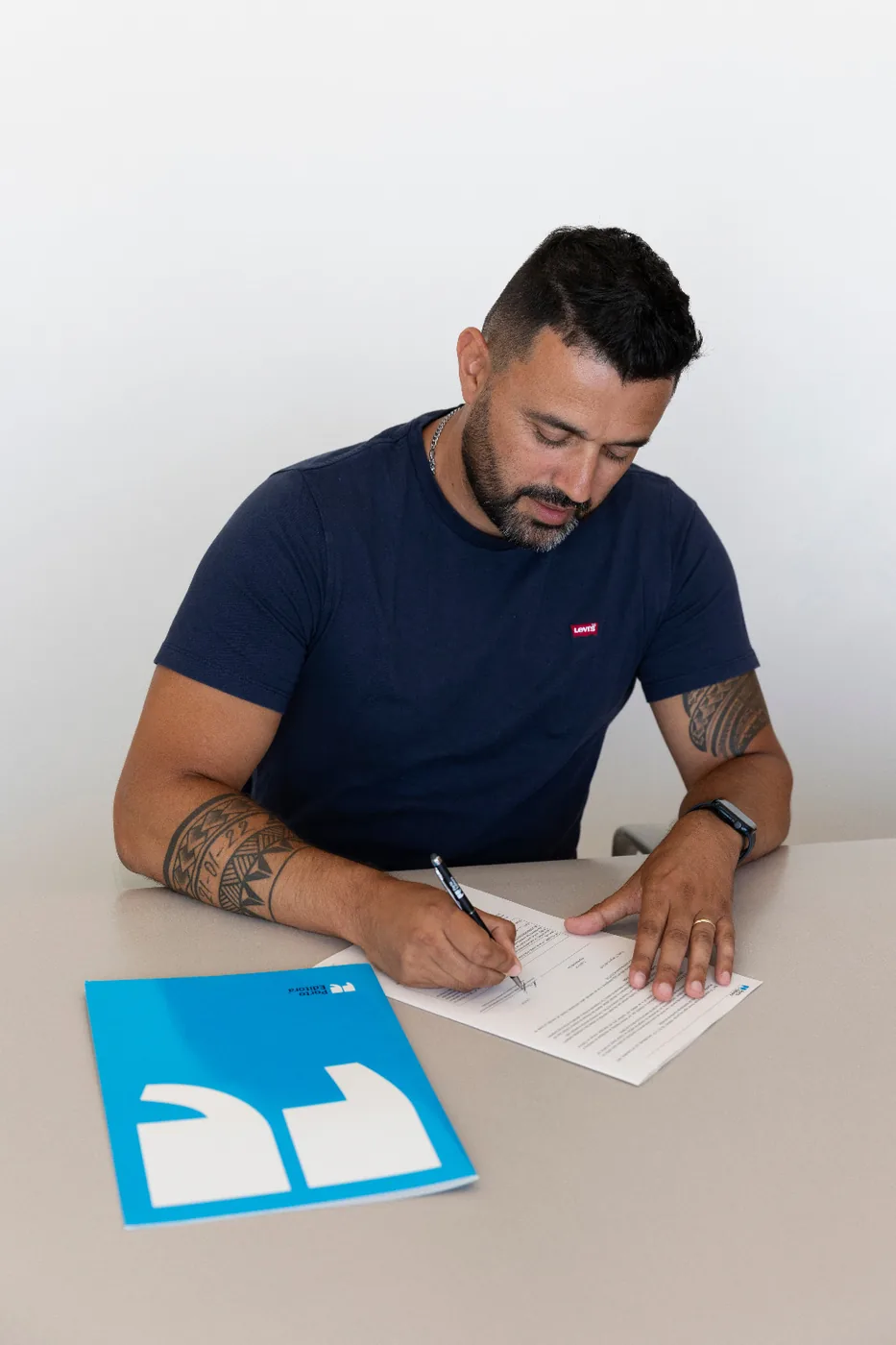 André Braga a assinar o contrato de edição, com uma pasta da Porto Editora pousada na mesa.